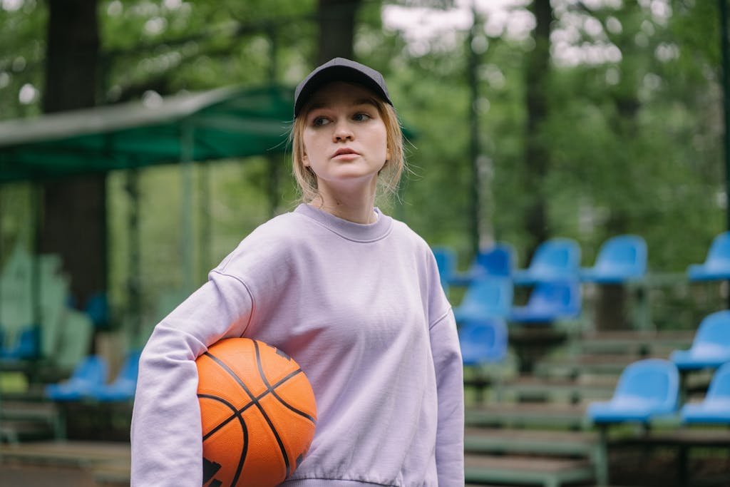 Das Mädchen, das Basketball spielt, trägt eine blaue Baseballmütze.