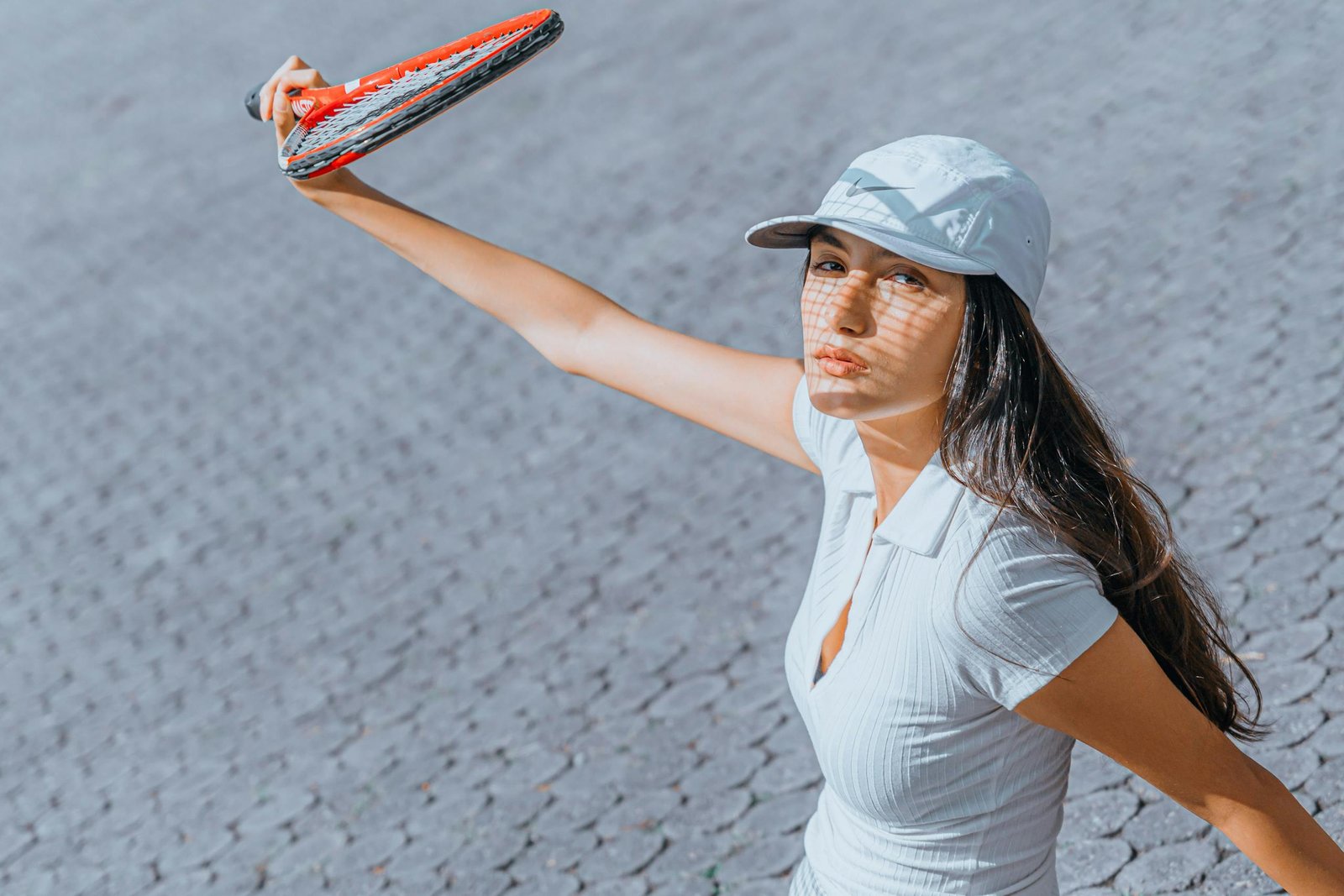 La chica que juega al tenis lleva un sombrero blanco para protegerse del sol