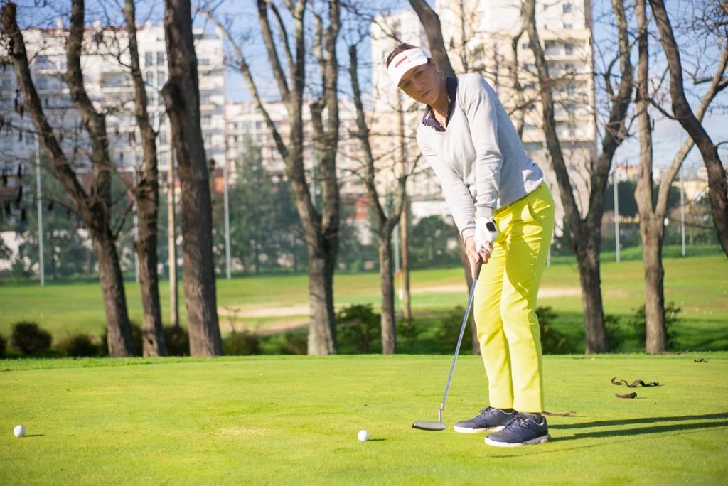A woman wearing a visor cap playing golf.